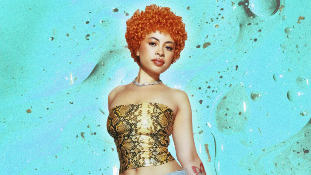 A person with curly orange hair wearing a snake-print top, standing confidently in front of a teal and gold abstract background.